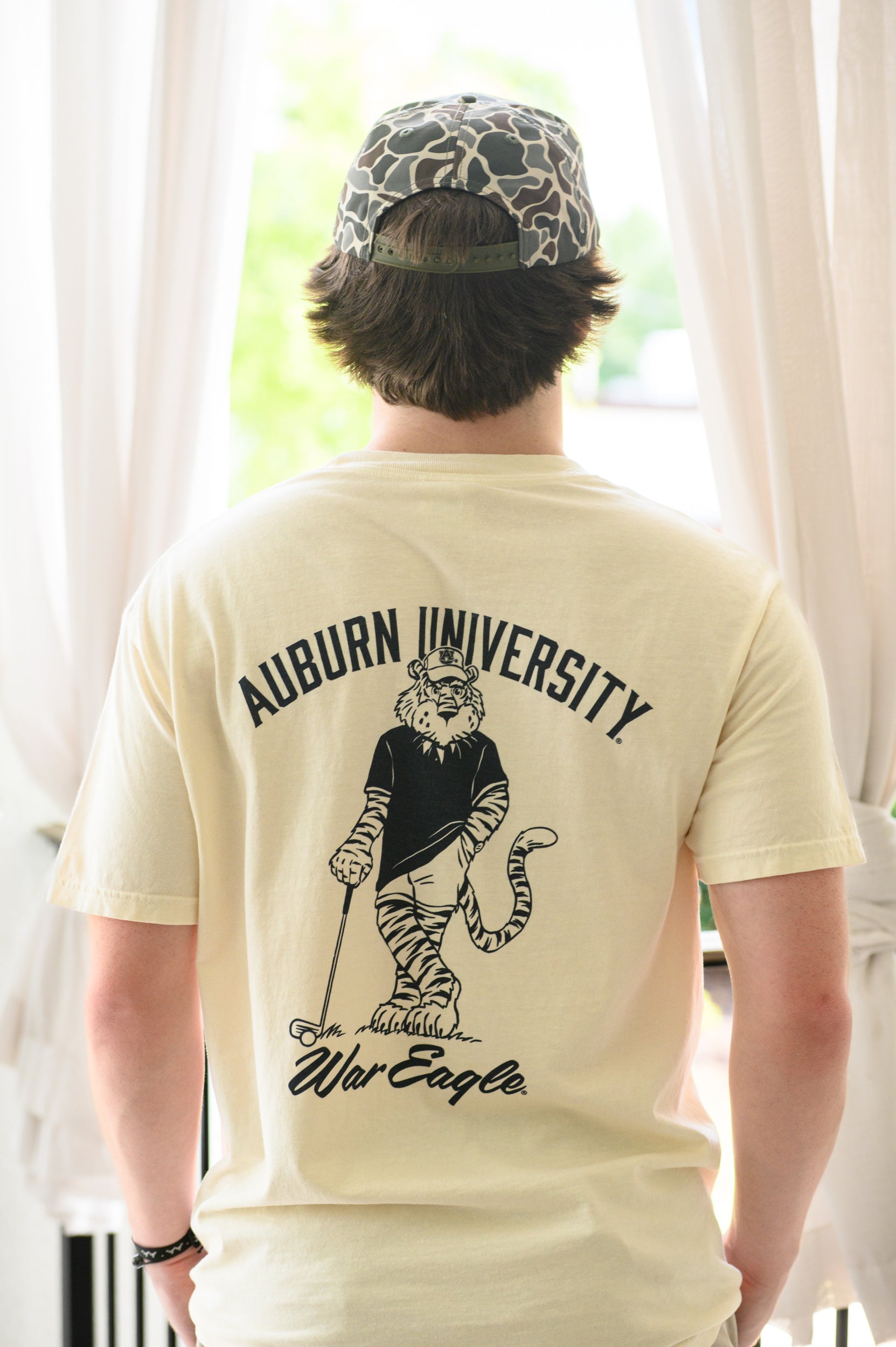 Auburn University Ivory T-Shirt with an image of Aubie leaning against a golf club between Navy Text "Auburn University" and "War Eagle"
