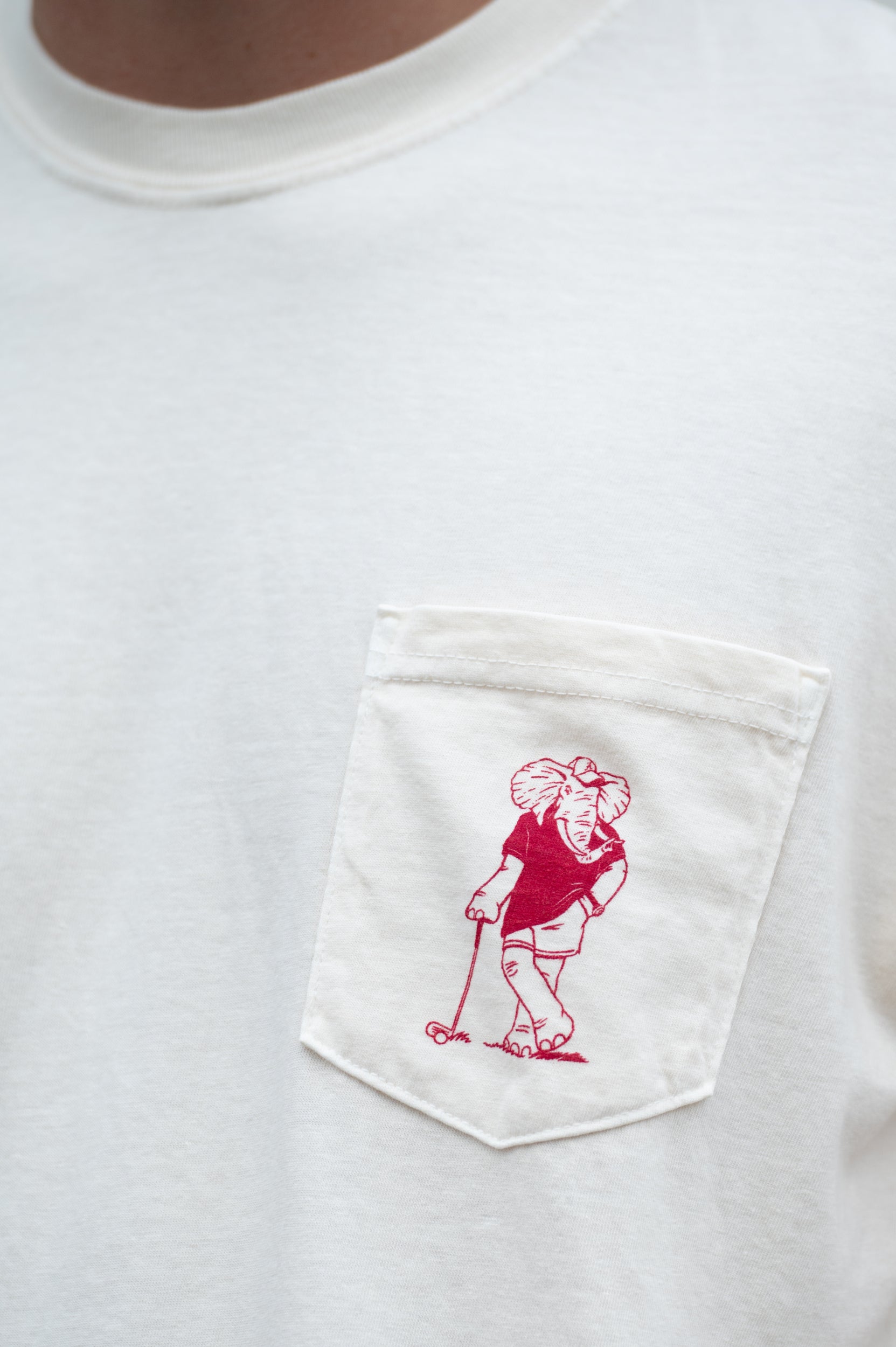 University of Alabama Ivory T-Shirt with an image of Big Al leaning against a golf club between Red Text "University of Alabama" and "Roll Tide Roll"