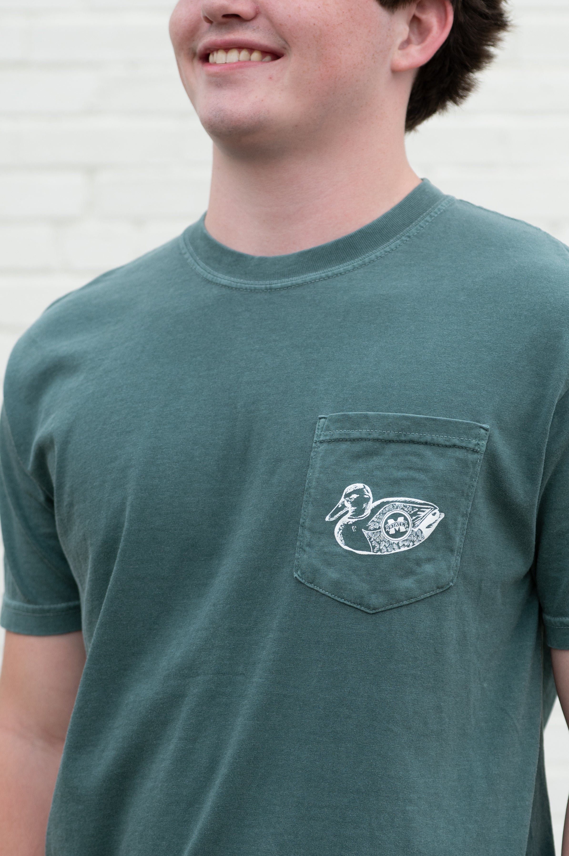 Mississippi State Dark Green T-Shirt with an image of Bully wearing hunting gear with a dog in a boat in the swamp