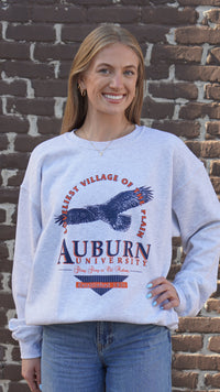Auburn University Grey Sweatshirt with an image of an eagle flying under Orange text “Loveliest Village of the Plains” and above text “Auburn University”