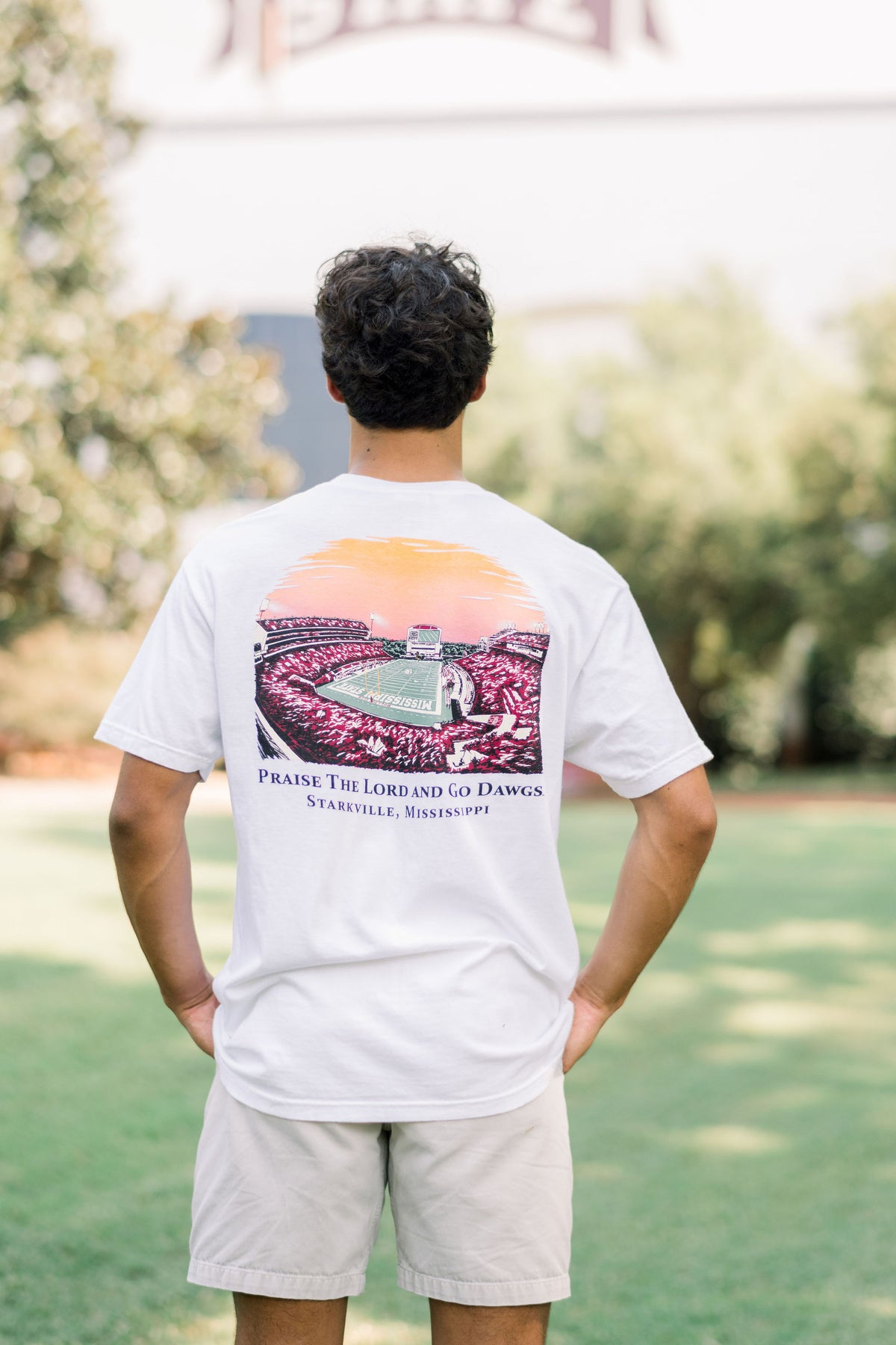 Mississippi State White T-Shirt with an image of the sun setting over the crowded Davis-Wade Stadium above text “Praise The Lord And Go Dawgs”