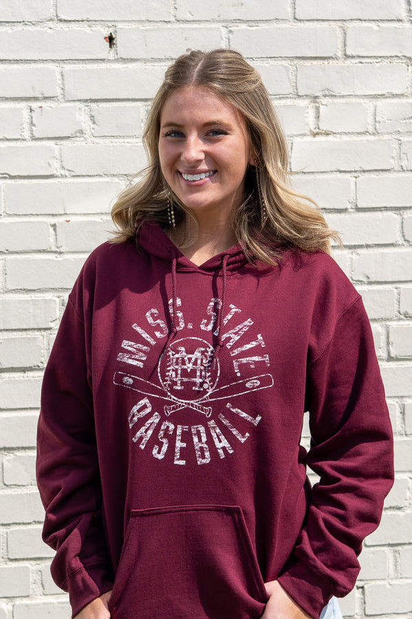 Woman wearing a maroon hoodie with 'Miss. State Baseball' text against a white brick wall.