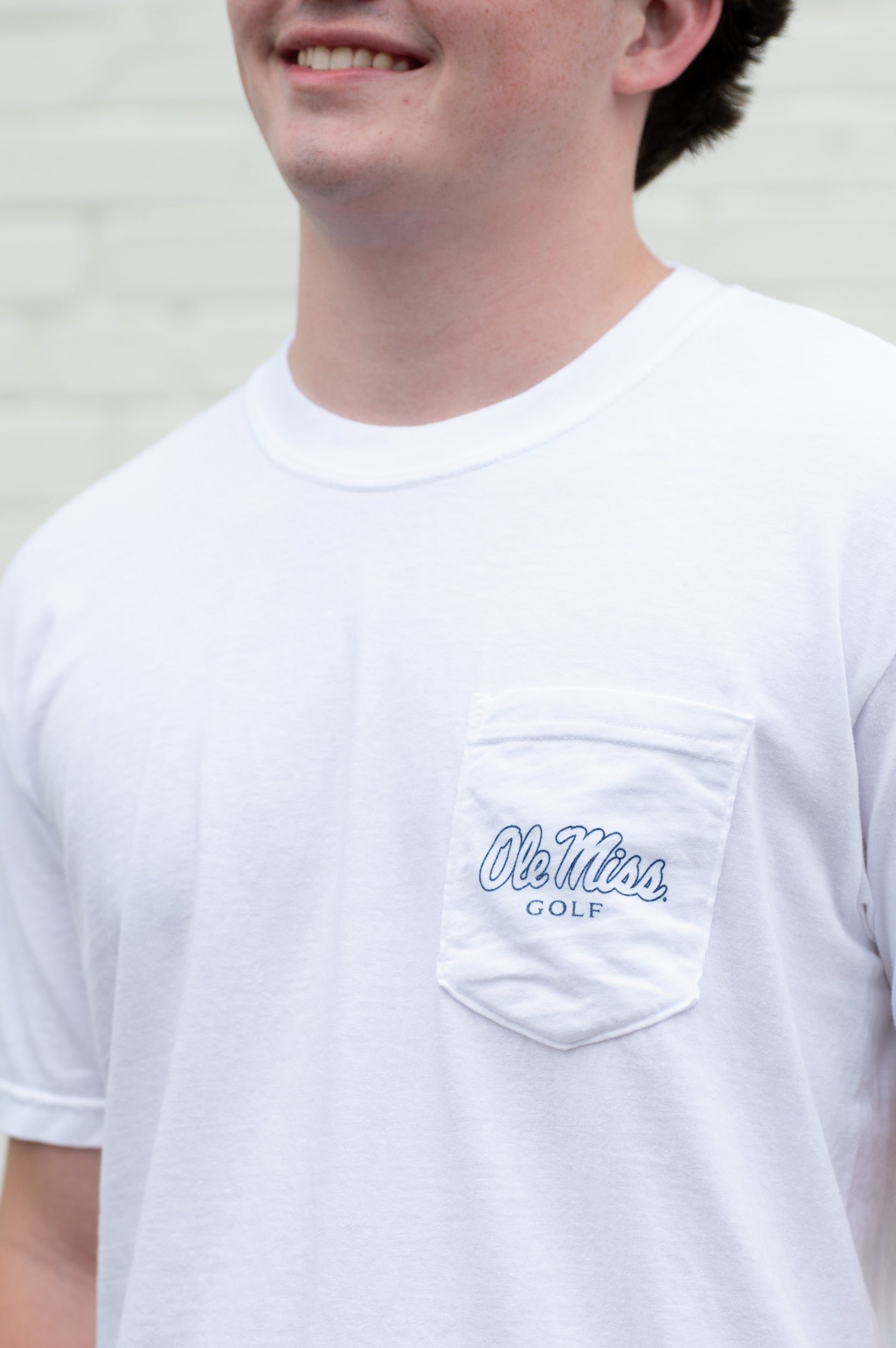 Ole Miss White T-Shirt with an image of a golf club carrying bag with the Rebels Logo