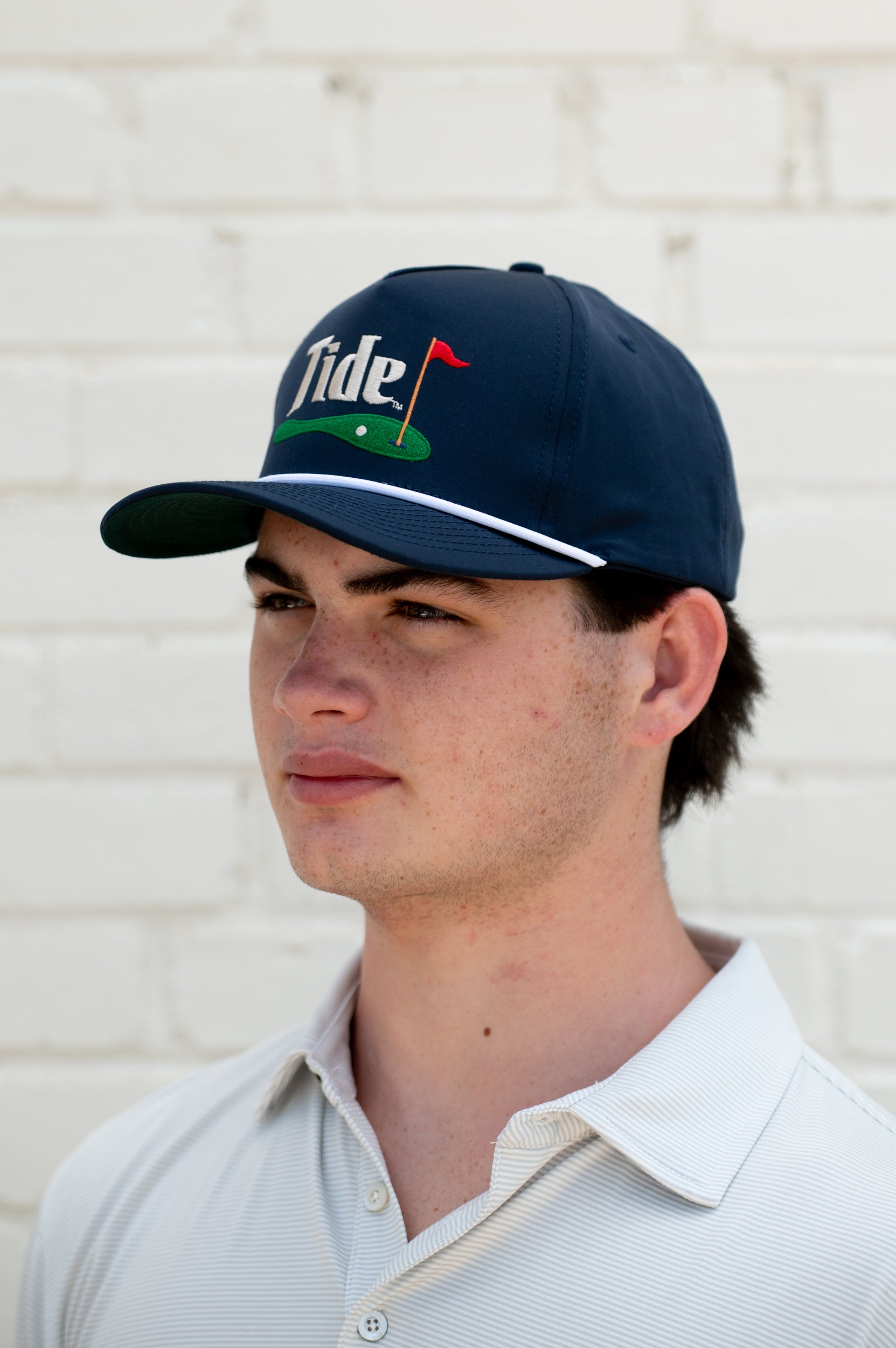 University of Alabama Navy Hat with a White Rope and White text “Tide” above an image of a golf hole