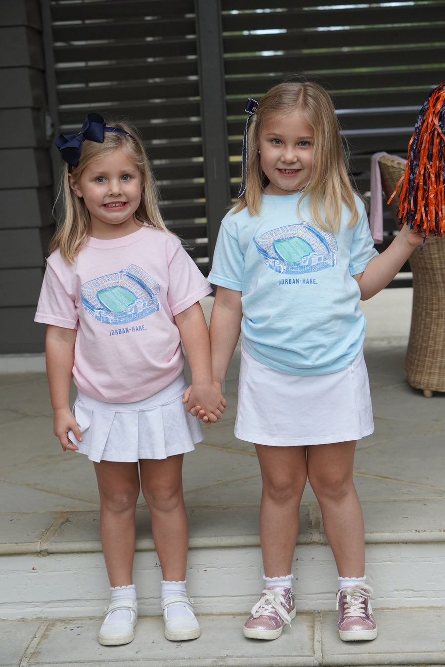 Auburn University Light Pink and Light Blue Youth T-Shirts with a watercolor illustration of Jordan-Hare Stadium